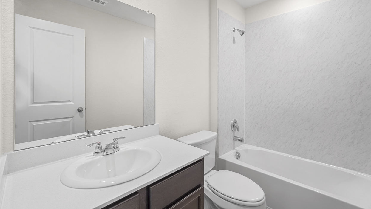 a bathroom with dark cabinets and a bathtub