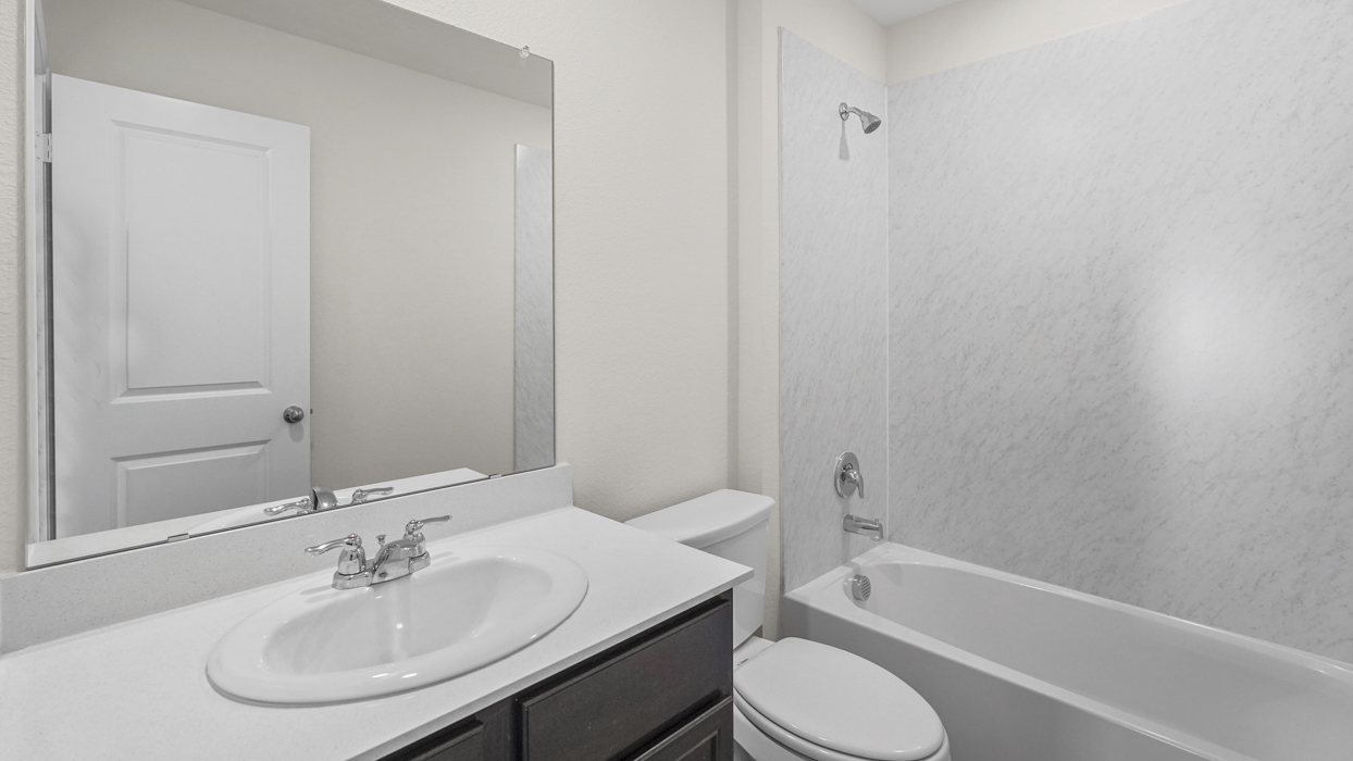 a bathroom with dark cabinets and a bathtub