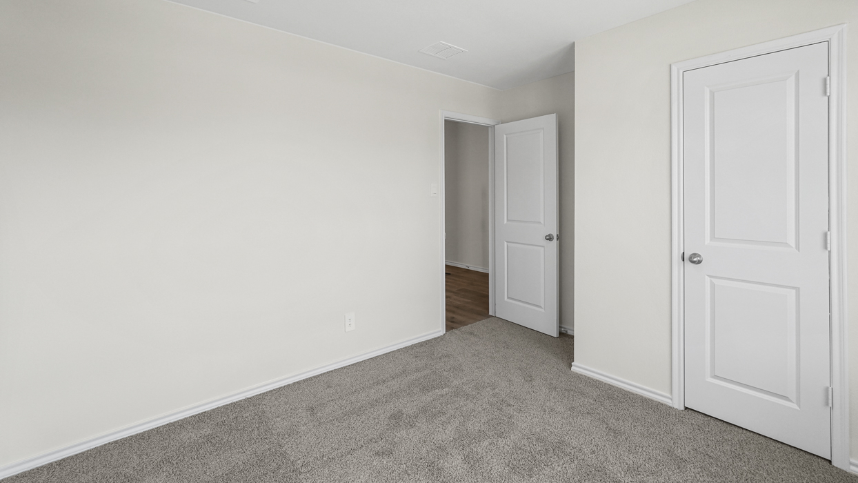 an empty bedroom with gray carpet and white walls