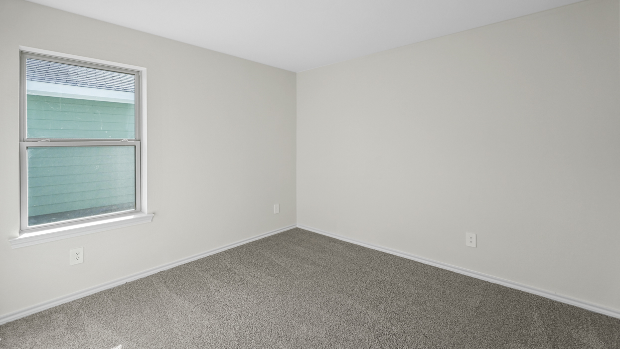 an empty bedroom with gray carpet and white walls