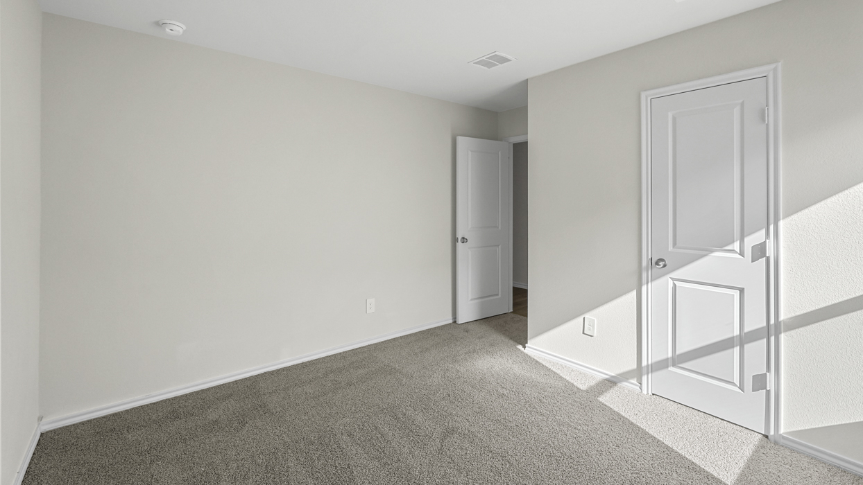 an empty bedroom with gray carpet and white walls