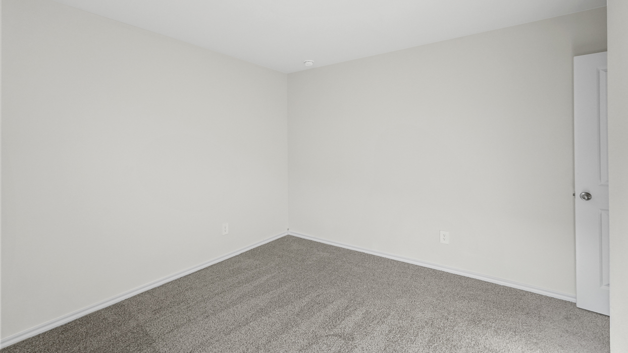 an empty bedroom with gray carpet and white walls