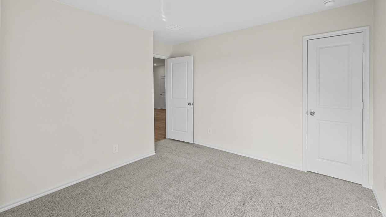 an empty bedroom with gray carpet and white walls