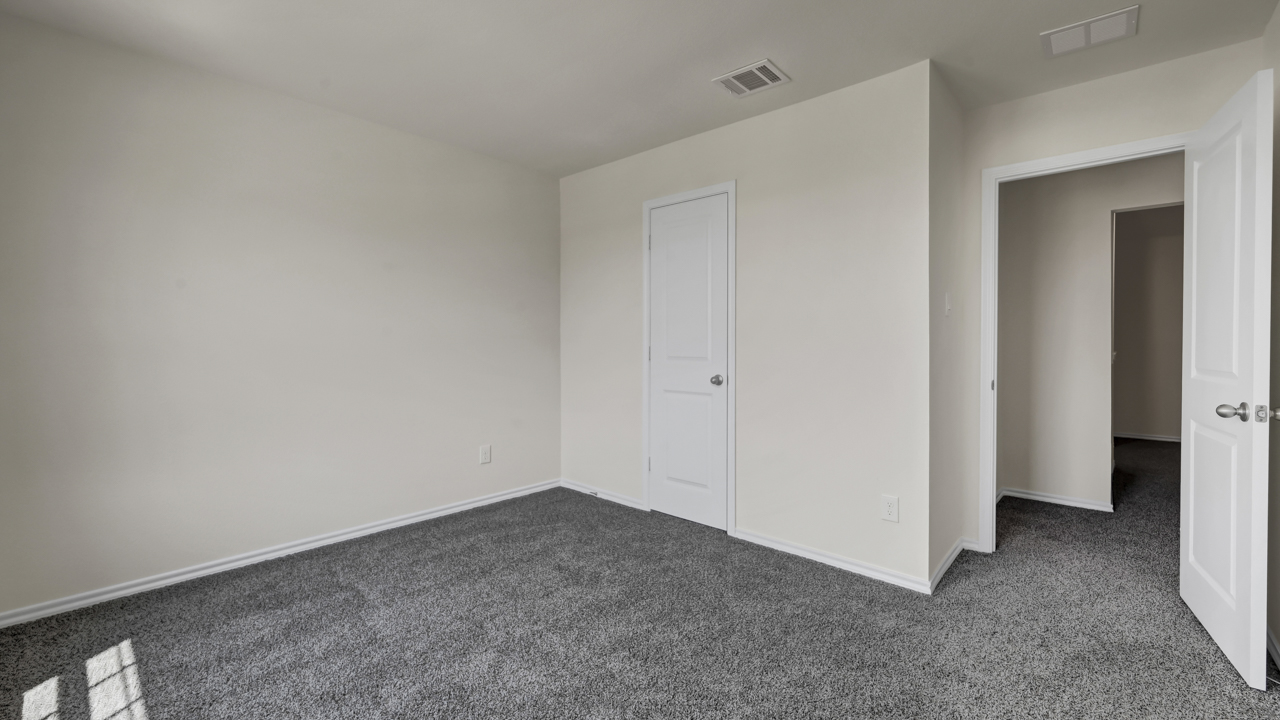 an empty bedroom with gray carpet white walls and windows