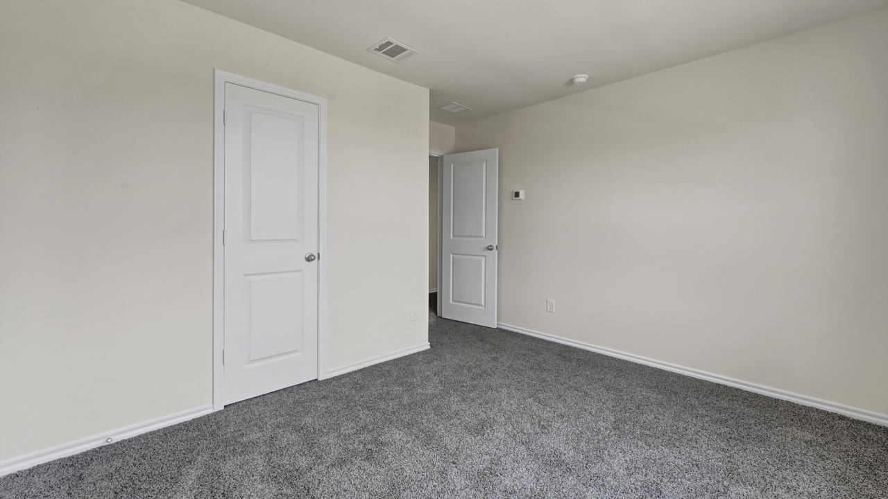 an empty bedroom with gray carpet white walls and windows