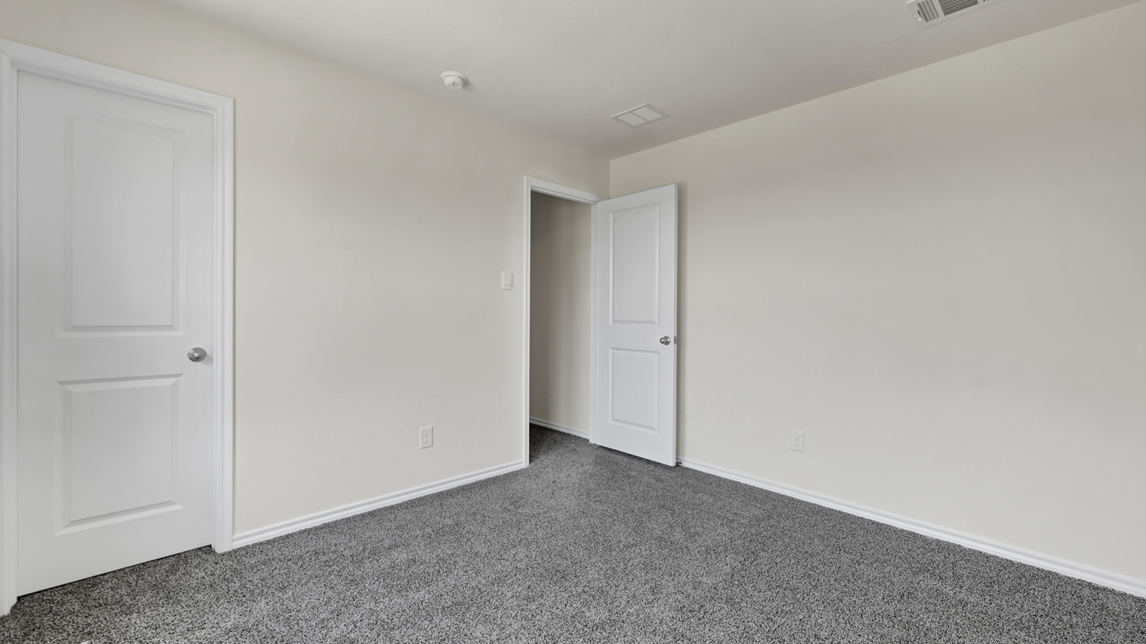 an empty bedroom with gray carpet white walls and windows