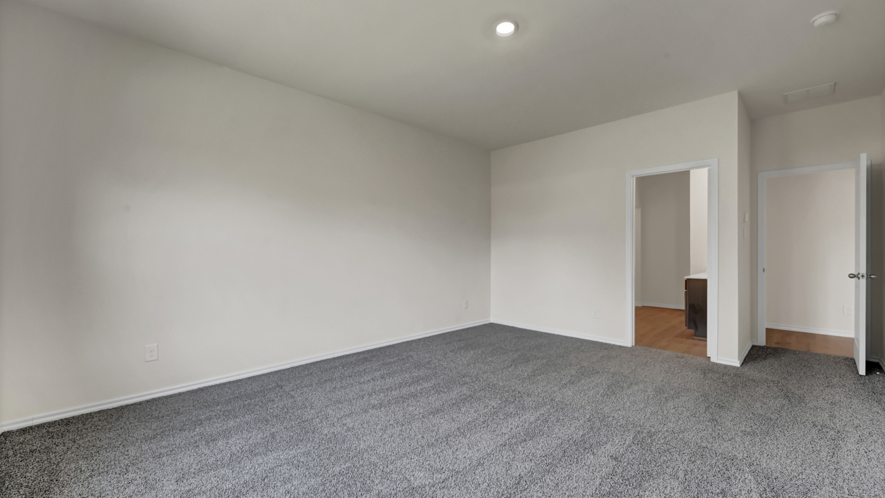 an empty bedroom with gray carpet white walls and windows