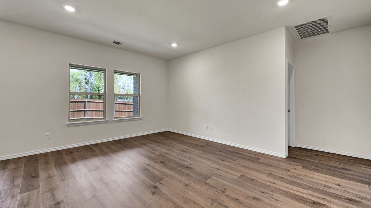 an open living area with wood floors white walls and windows