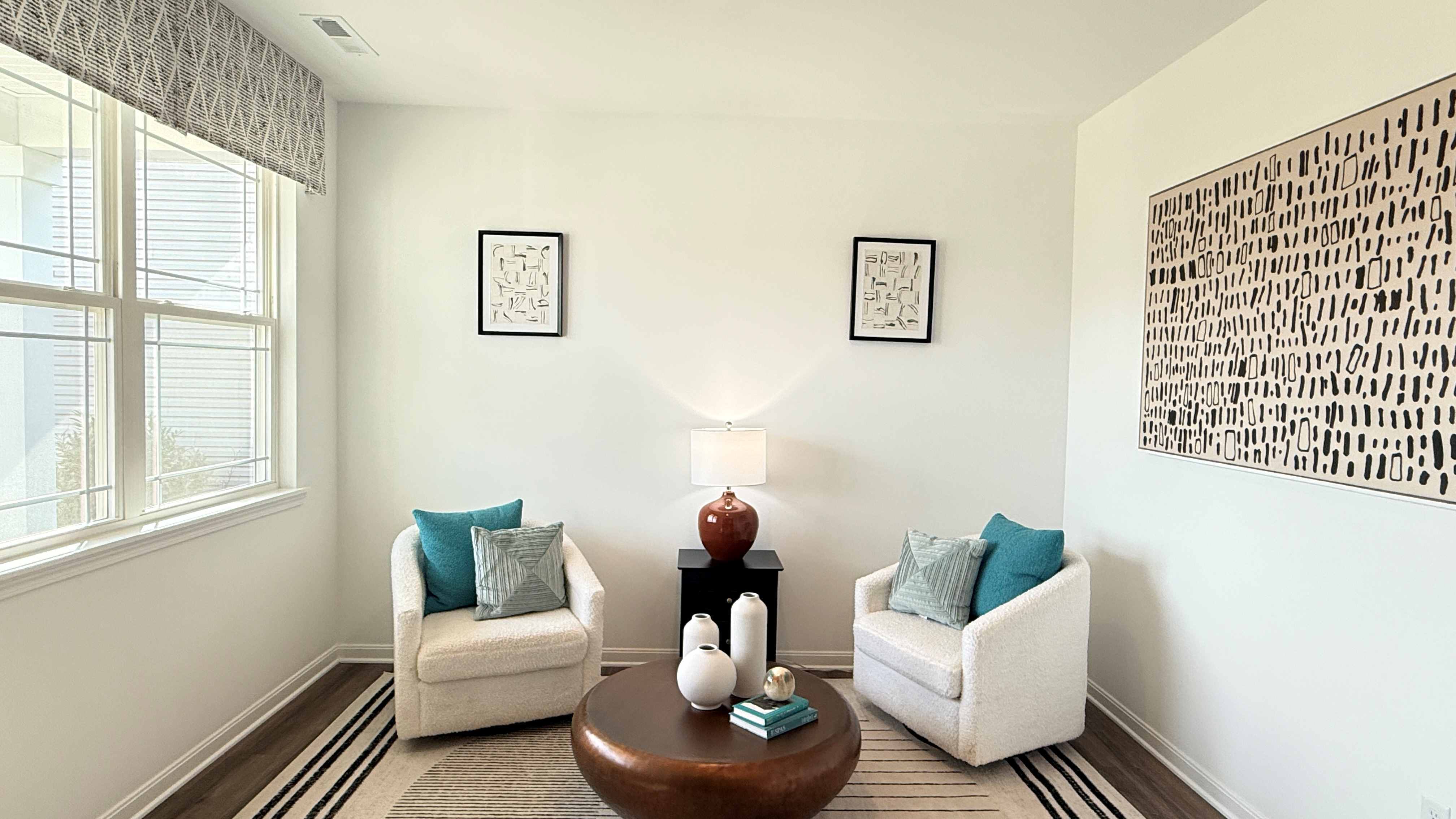 First floor flex room with 2 accent chairs, table, and lamp.