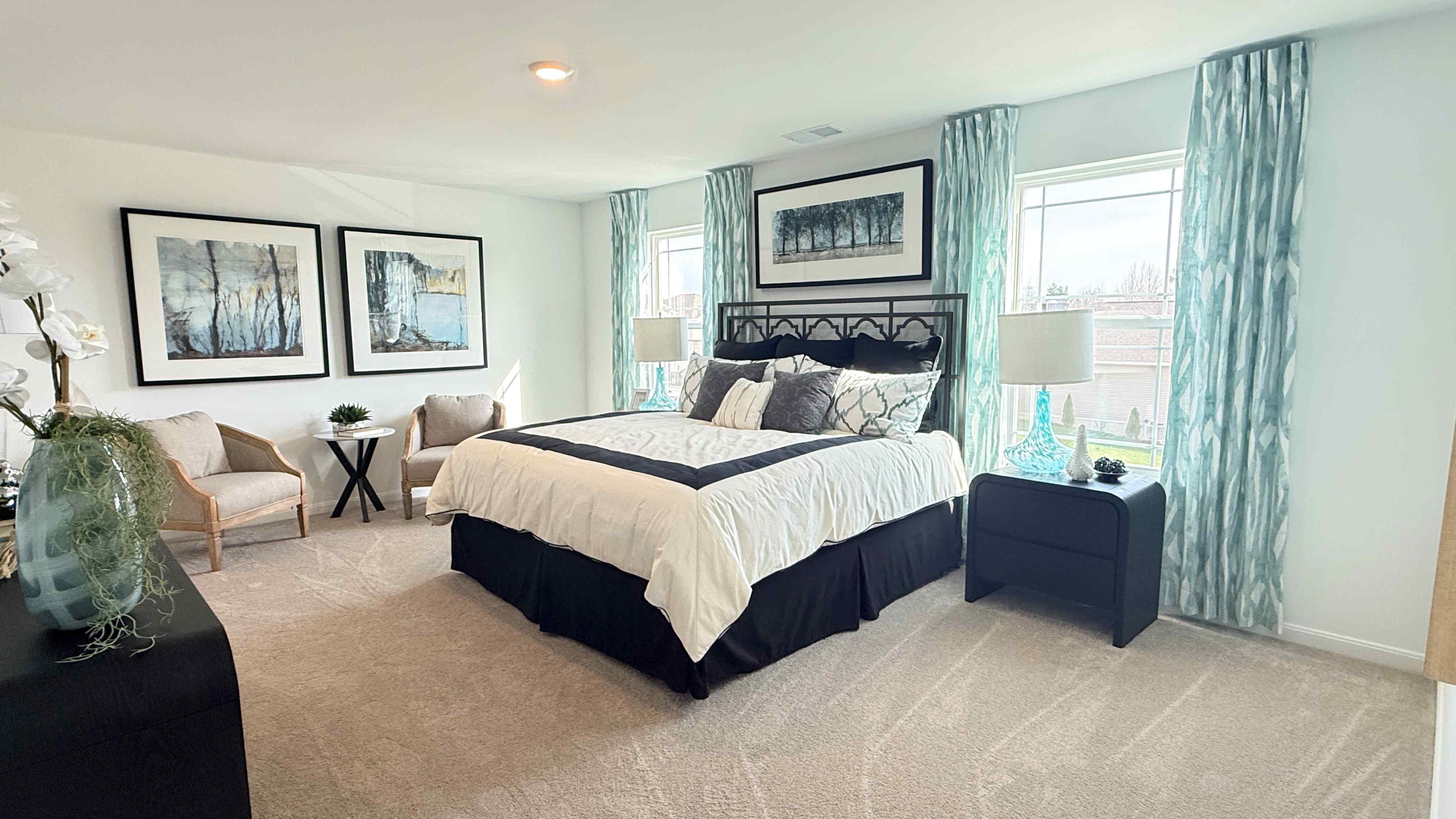 Upstairs primary bedroom with king size bed, 2 nightstands, 2 single windows, 2 accent chairs, and dresser.