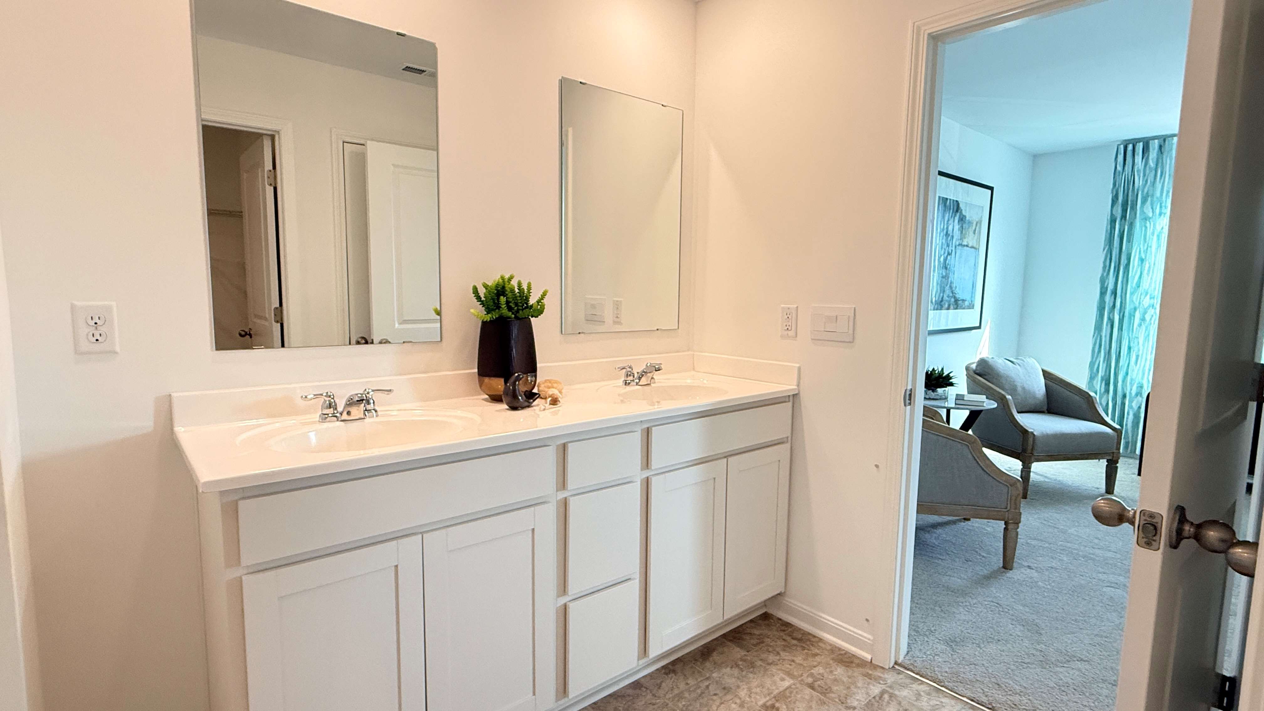 Other view of primary bathroom. White vanity cabinets.