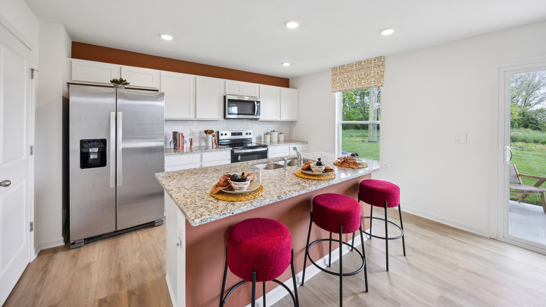 Spacious kitchen with white cabinets, quartz countertops, stainless steel appliances, and a center island.