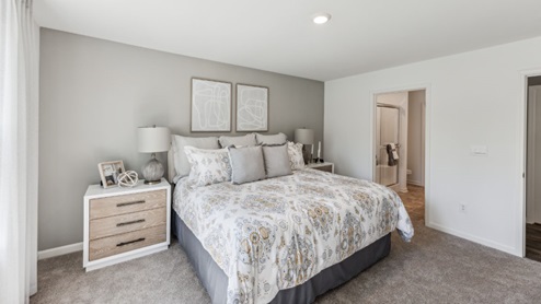 Bedroom with beige carpet, bed and bedside table