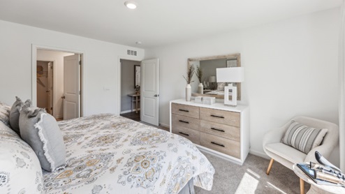 Bedroom with beige carpet and dresser, view with door