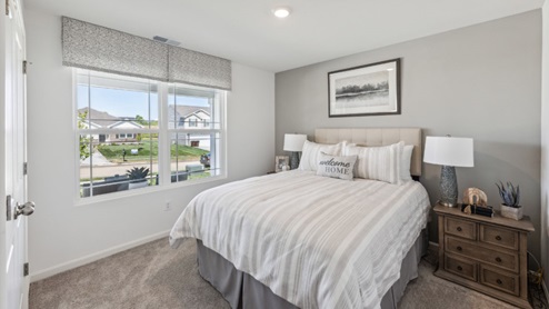 Bedroom with beige carpet, window, bed and bedside table