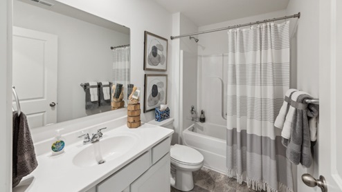 Bathroom with vanity, grey cabinet with white counter, tub/shower combo with grey curtain