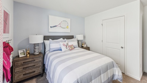 Bedroom with bed, brown bedside table, view of closed closet with white door