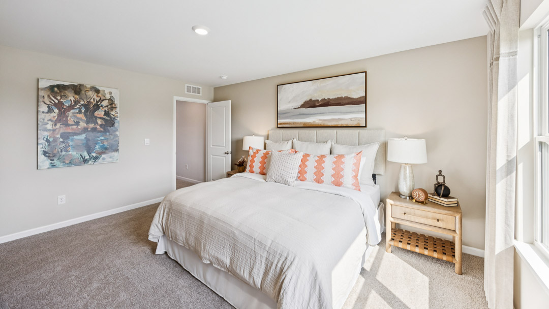 Other view of primary bedroom with bed, nightstands, and entry door