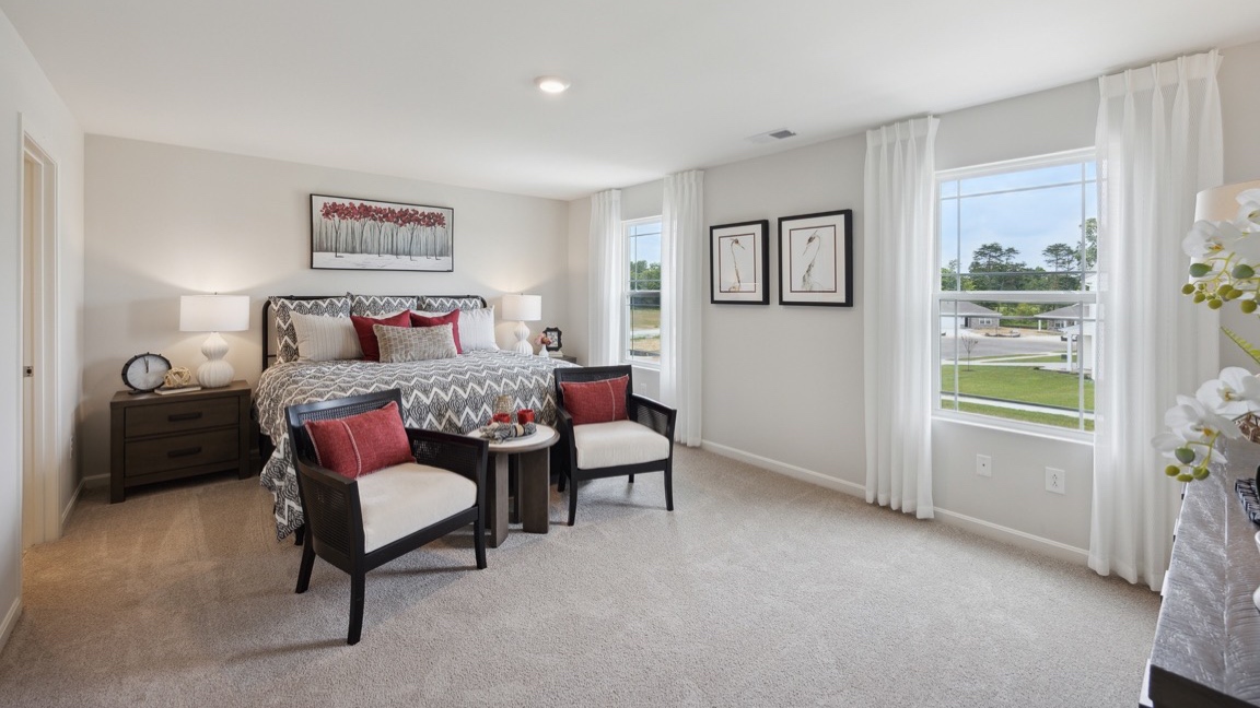 Upstairs primary bedroom with 2 single windows, king size bed, 2 nightstands, 2 accent chairs, and a dresser.