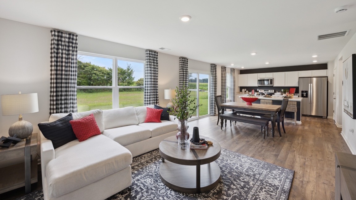 Living room with couch, coffee table, and double window overlooking the back yard.