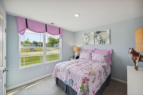 Bedroom with bed, grey walls, beige carpet and window with pink valance