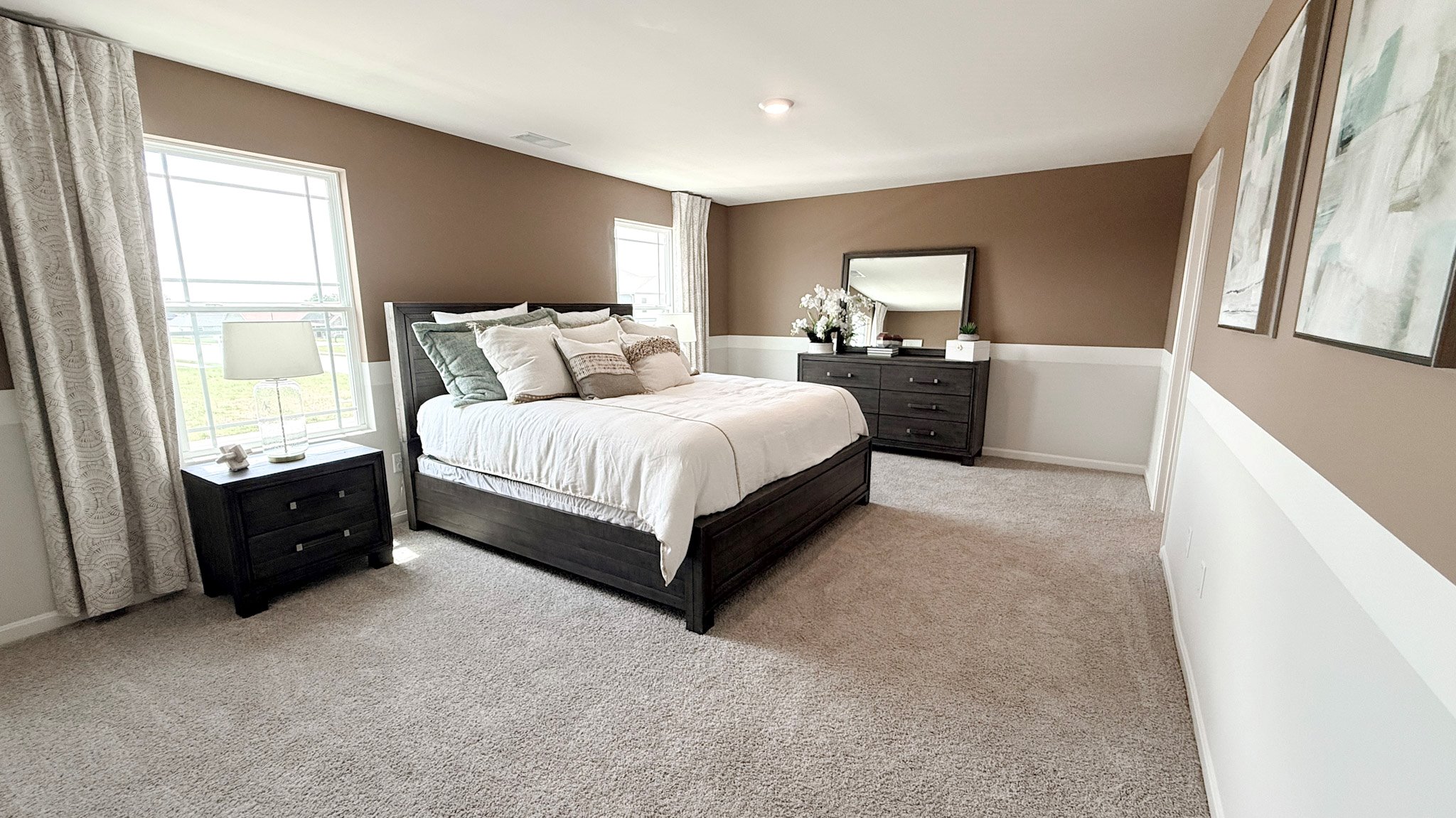 Second floor primary bedroom with two single windows, king size bed, two nightstands with lamps, and a dresser.