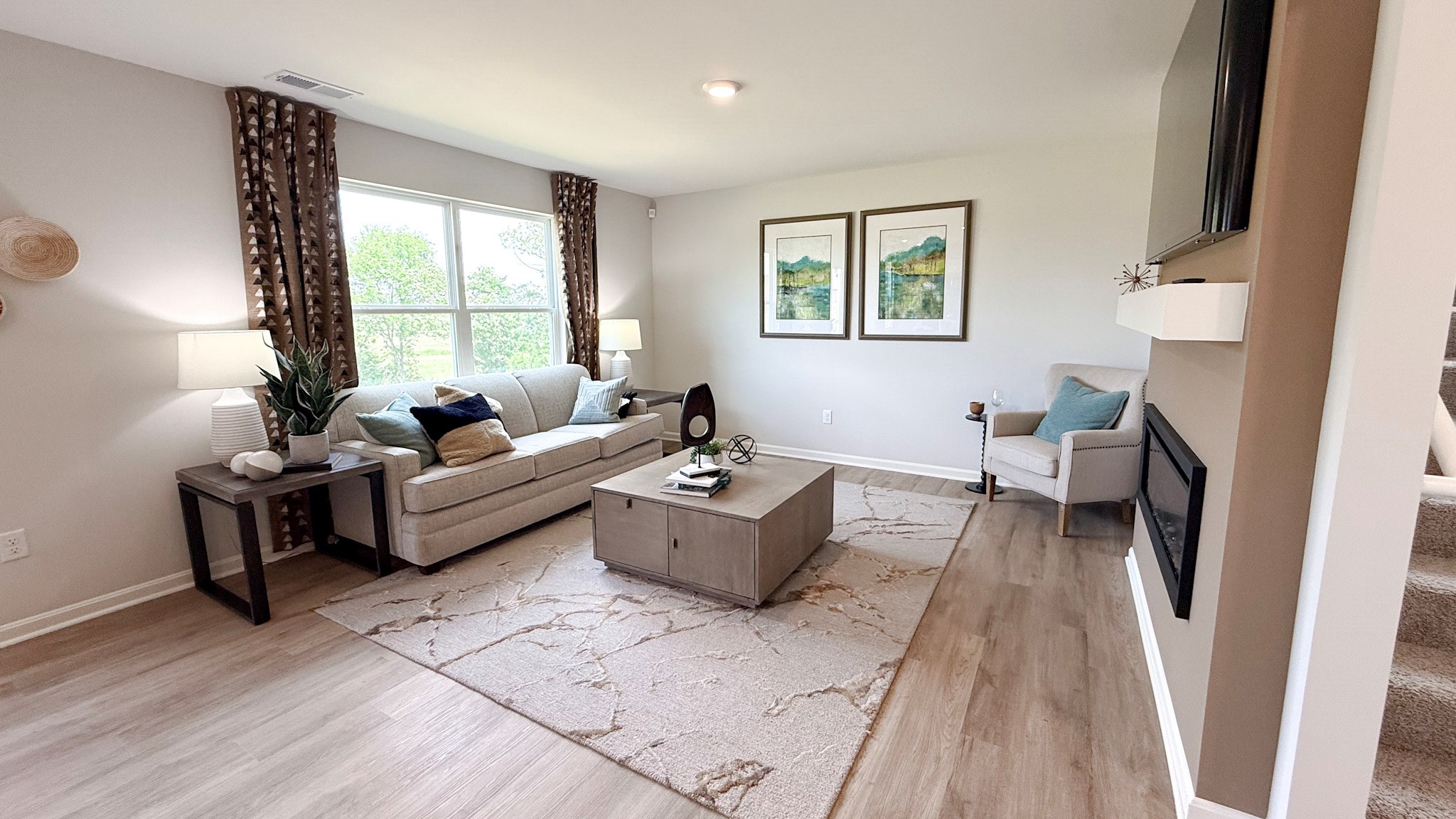 Living room with double window overlooking the backyard, couch, accent chair, coffee table, rug, and LVP flooring.
