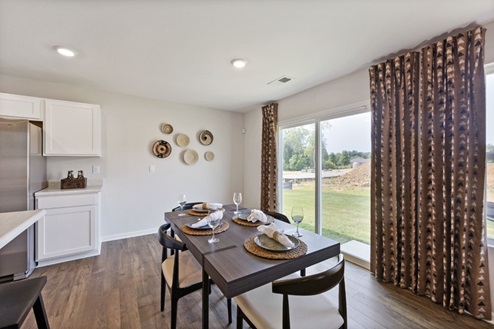 Casual dining room with large window with patterned curtains, table and chairs