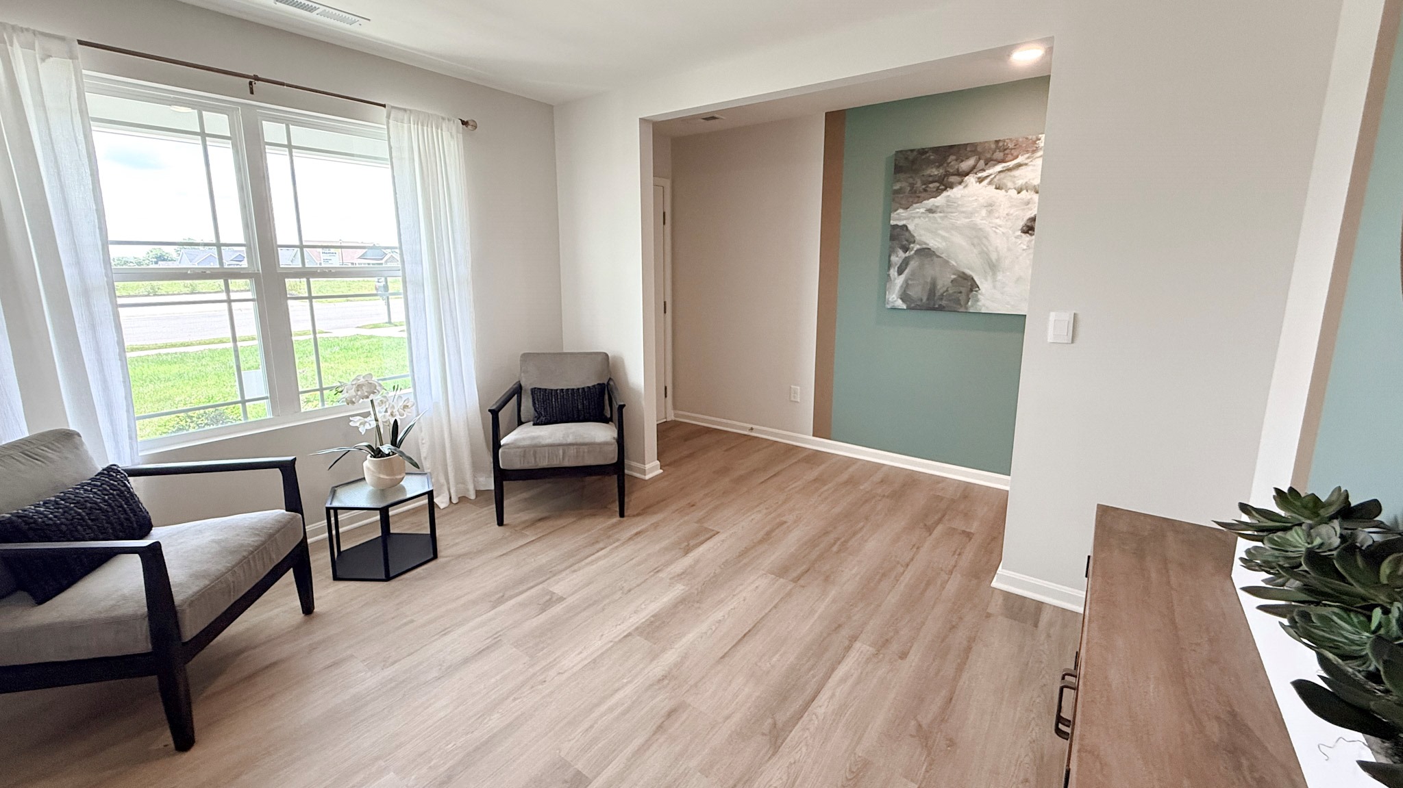 Flex room with double window, LVP flooring, and accent chairs.