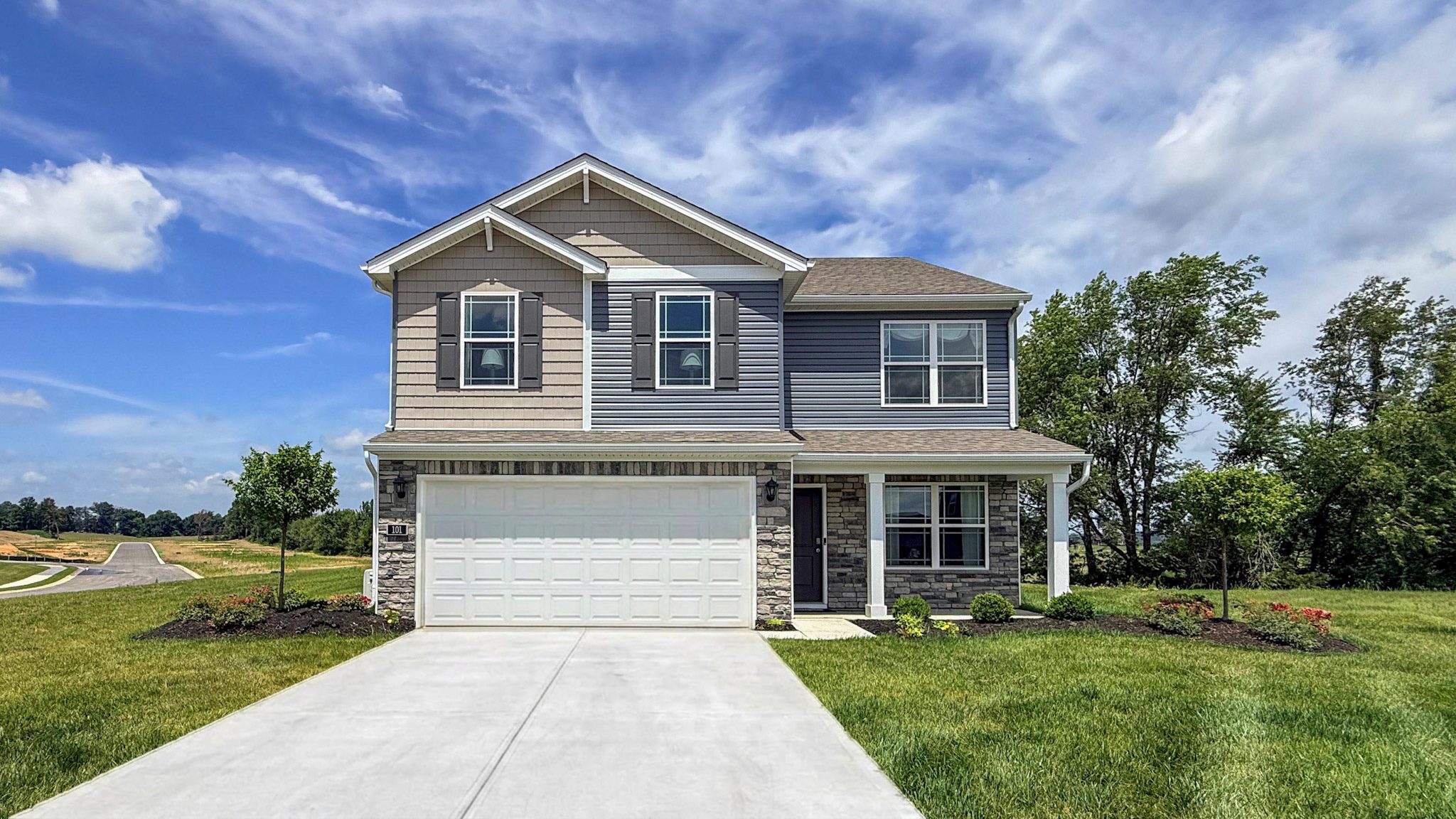 Ashton Park Bellamy model home with blue and beige siding, stone accents, a covered front porch, and a 2-car attached garage. Built by D.R. Horton Homes in Elizabethtown, Kentucky.