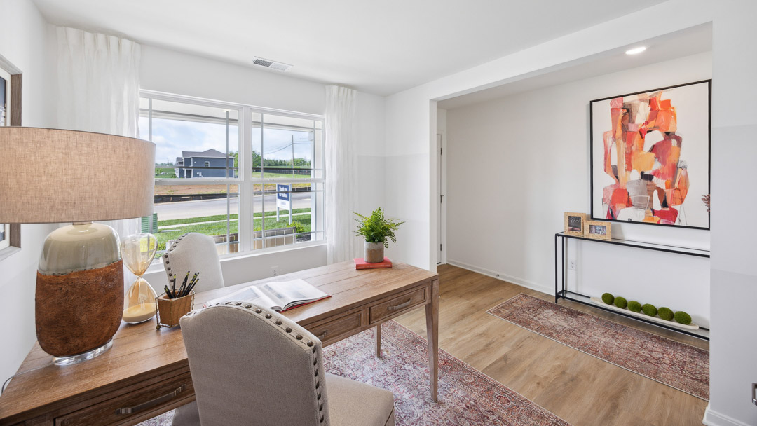 First floor flex room with desk, chair, and double window overlooking the front yard. Double opening to the front door area.