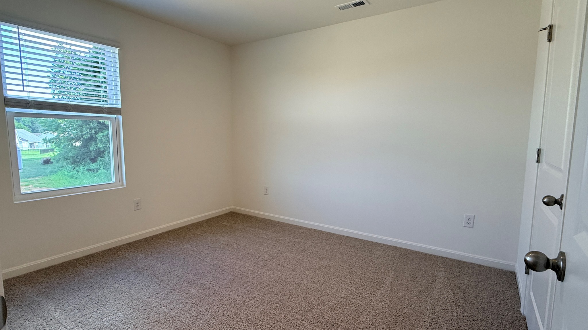 Second floor spare bedroom with single window and carpet flooring.