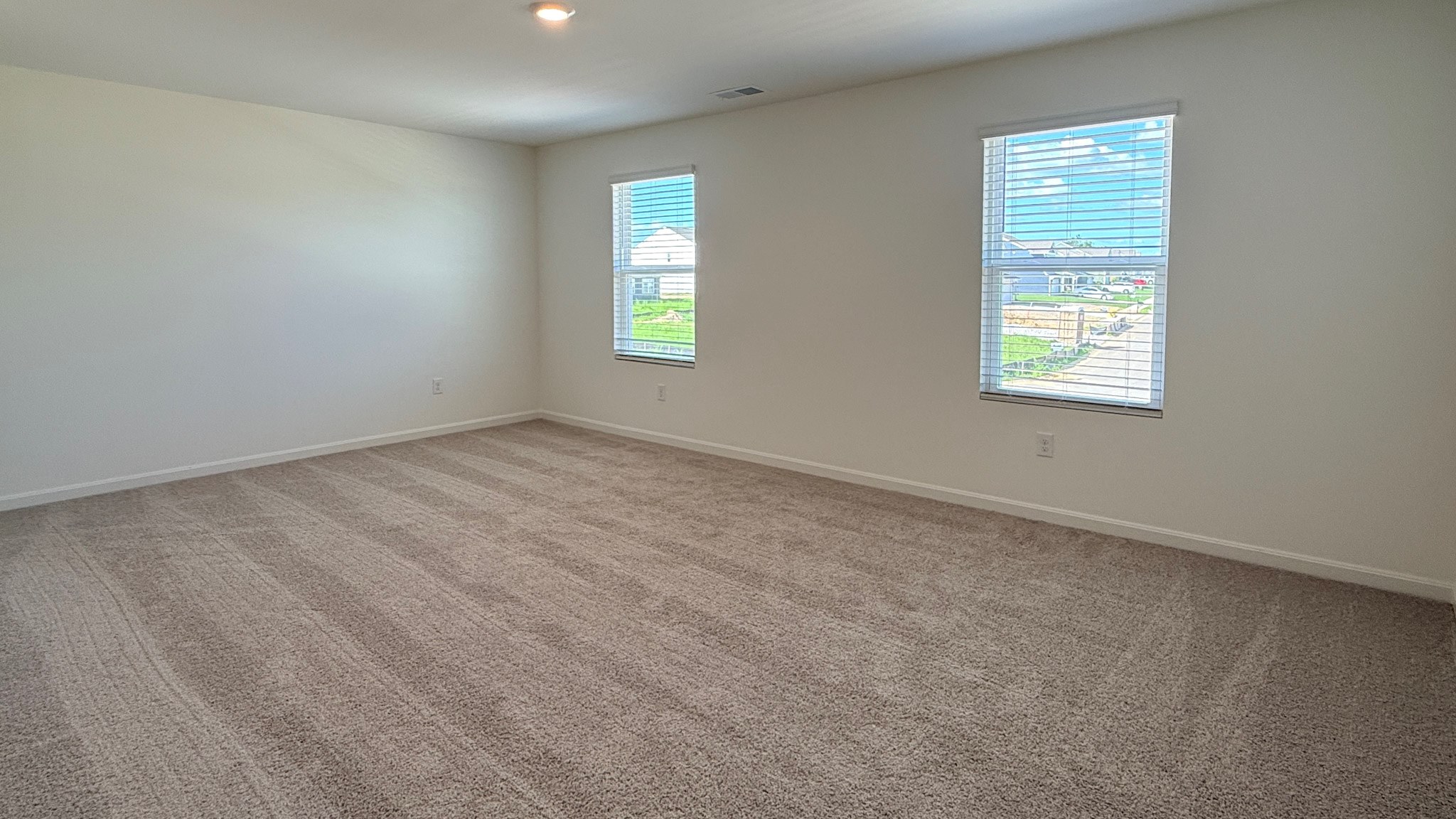 Second floor primary bedroom with two single windows and carpet.