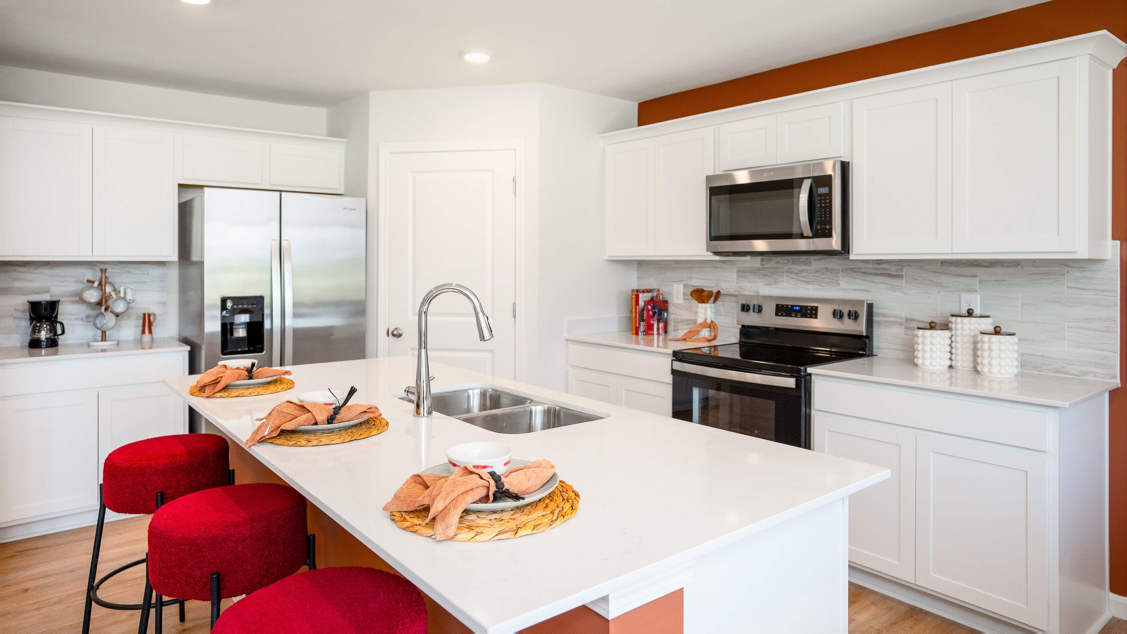 Spacious kitchen with white cabinets, quartz countertops, and stainless-steel appliances.