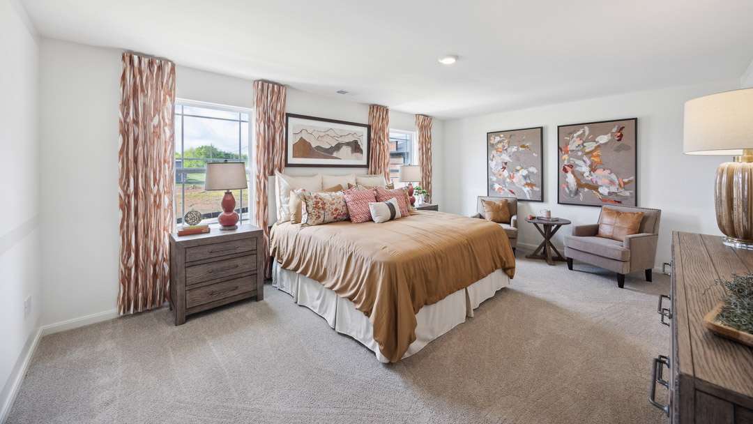 Second floor primary bedroom with two single windows, king size bed, two nightstands, dresser, and two accent chairs.