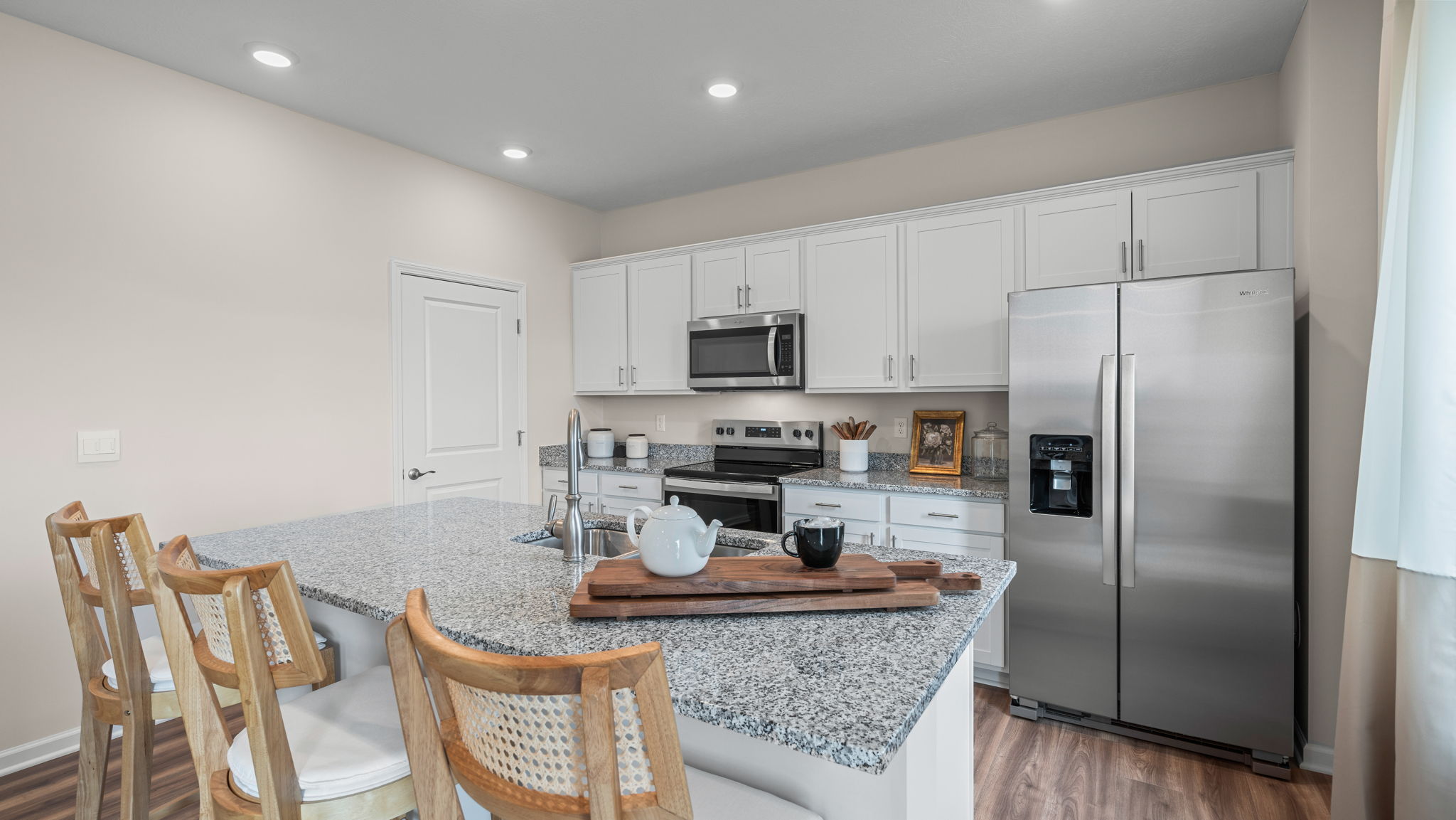 Other view of kitchen with white cabinets and stainless steel appliances.