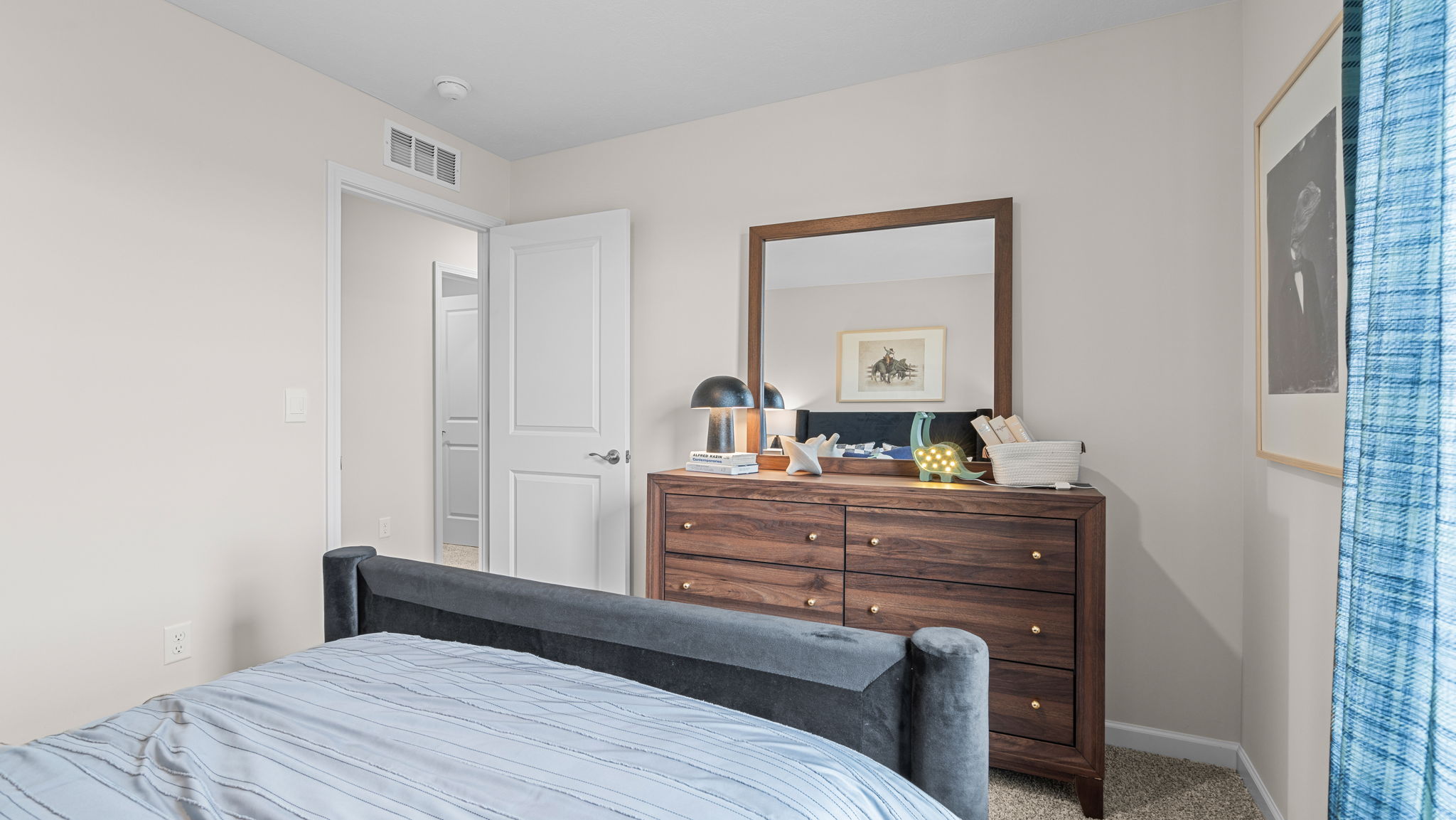 Other view of spare bedroom looking at the foot of the bed facing a dresser and bedroom entry door.