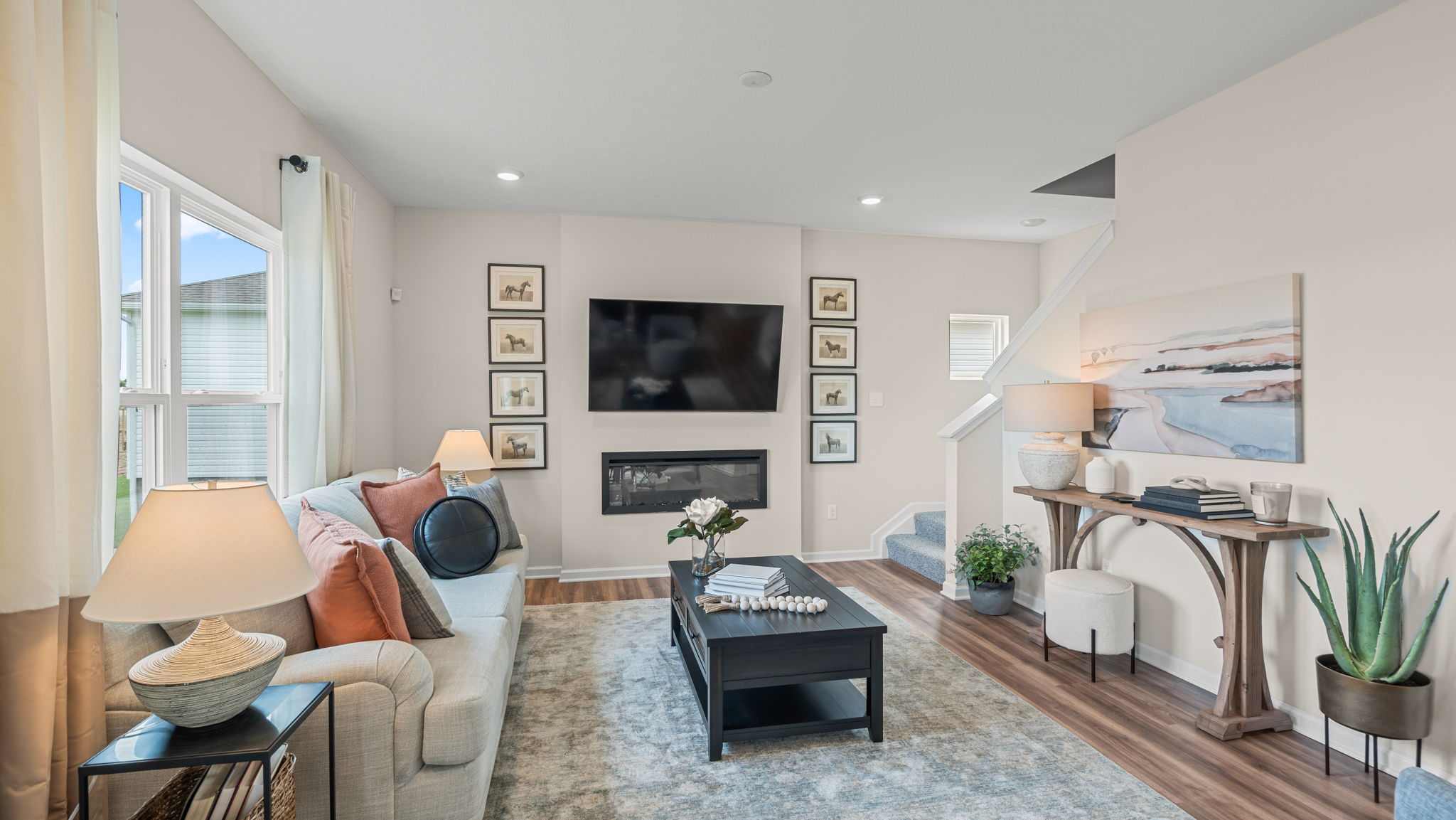 Living room with double window overlooking back yard. Couch, tv on wall, coffee table.
