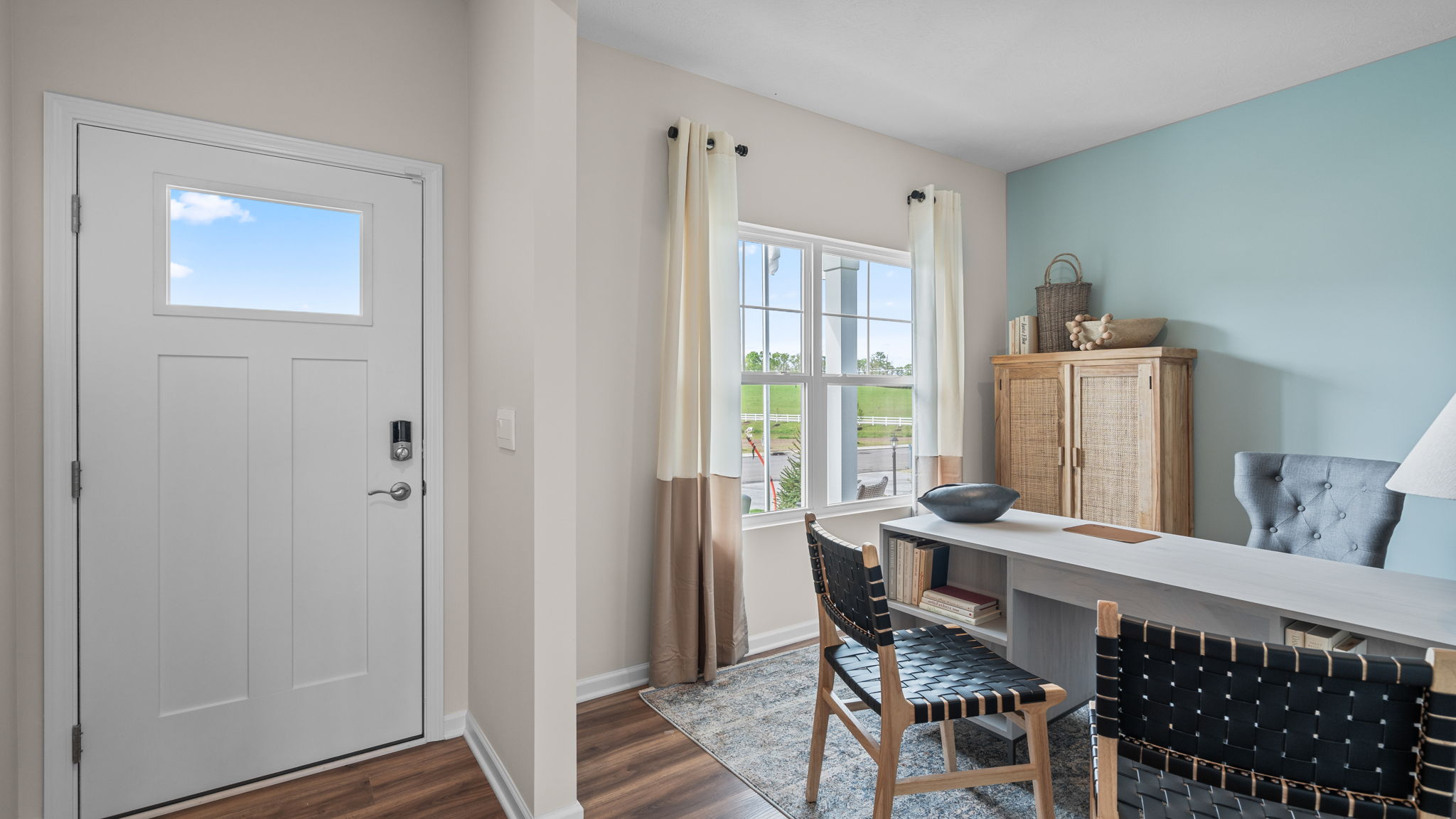 Standing in the foyer facing the front door and into the double opening into the flex room. Flex room is decorated as a home office.