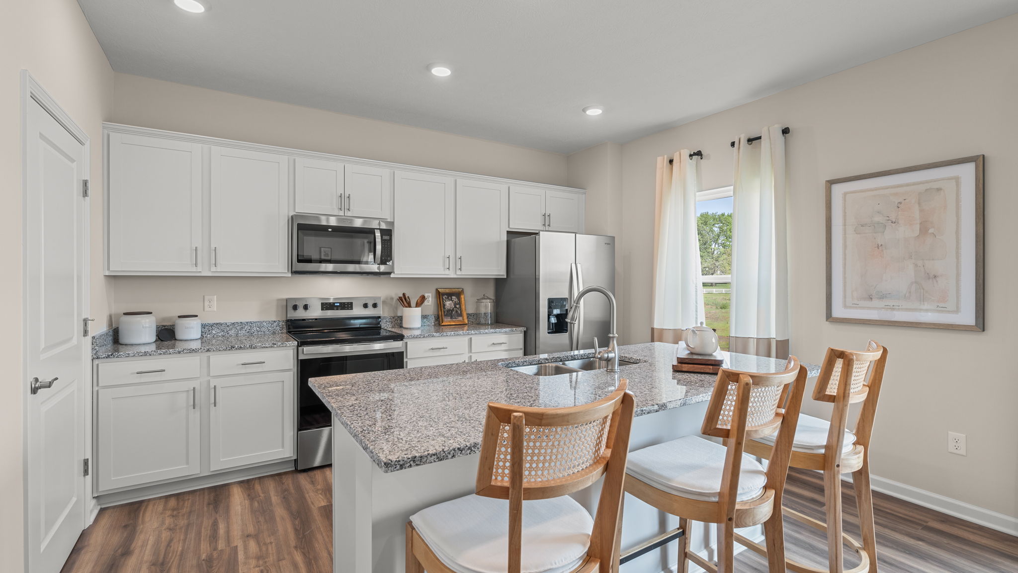 Spacious kitchen with center island and 3 barstools.