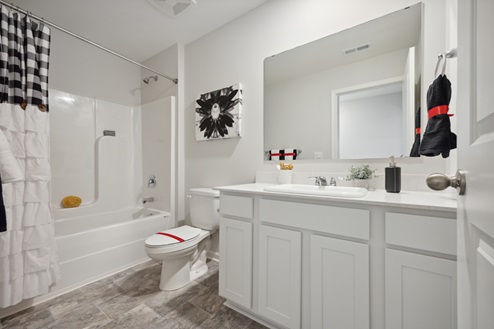 Secondary bathroom. White vanity with large mirror above. White tub/shower combo. Tile patterned vinyl flooring.