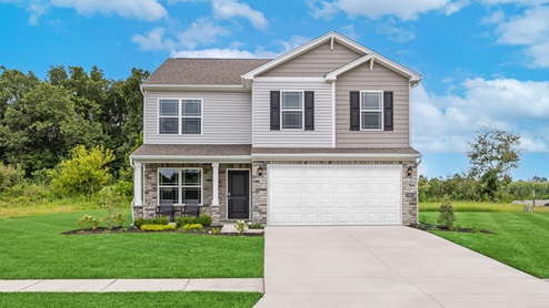 two story home with large windows on the left side of the home and small windows over the large white two car garage door. Home features gray and tan siding with dark shutters and a long driveway.