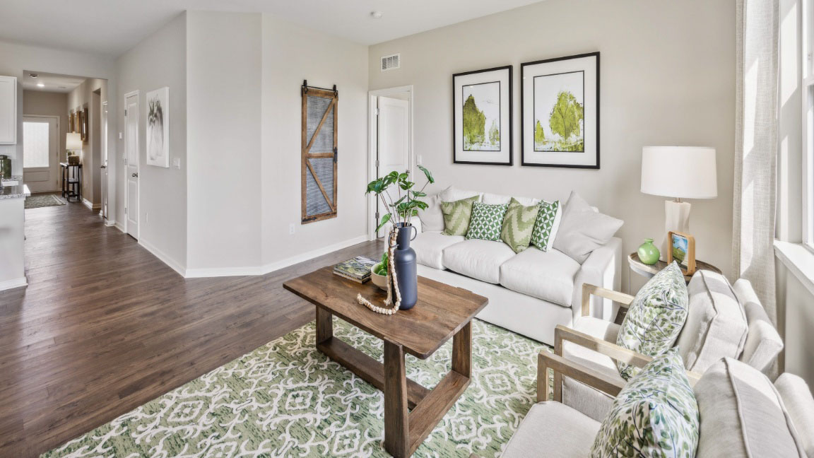 spacious living room featuring a white sofa, green rug, wooden tv stand, tv and a large window