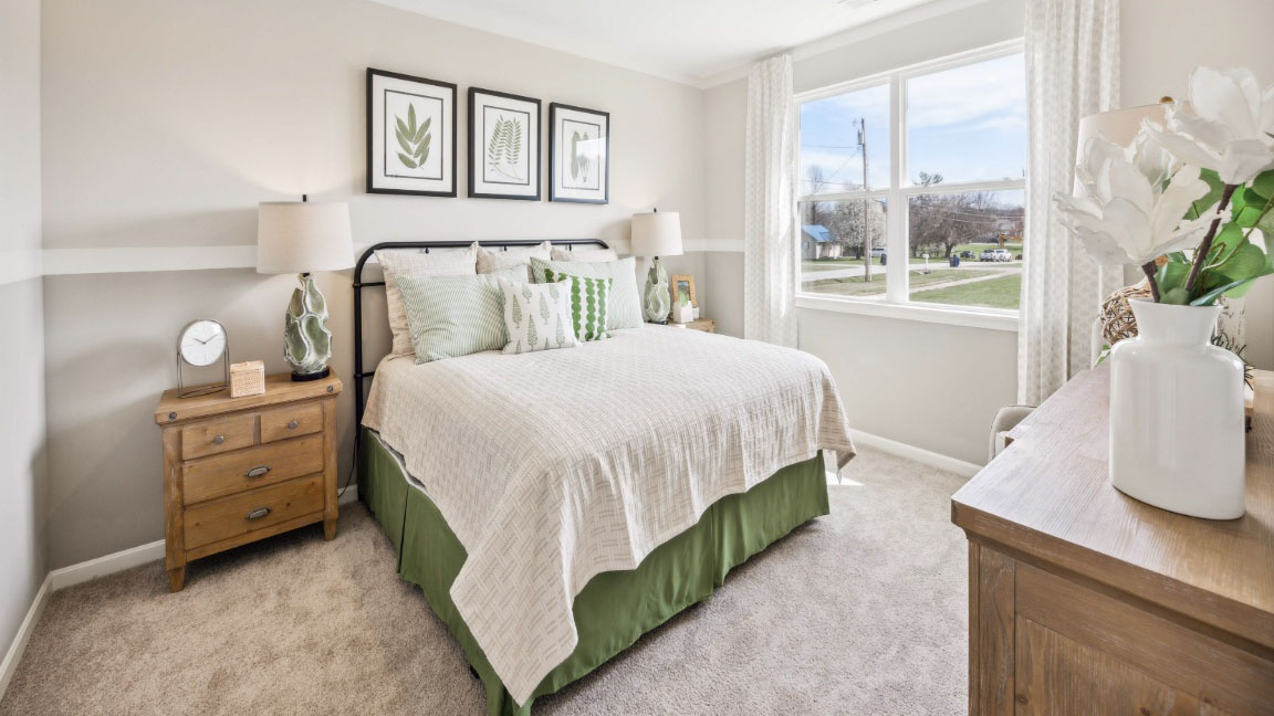 bedroom featuring a bed with 2 wooden night stands on either side, a large window, and green and white decor