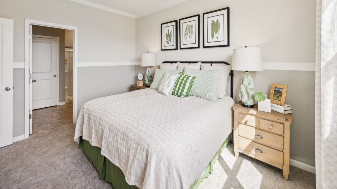 bedroom featuring a bed with 2 wooden night stands on either side, a large window, and green and white decor
