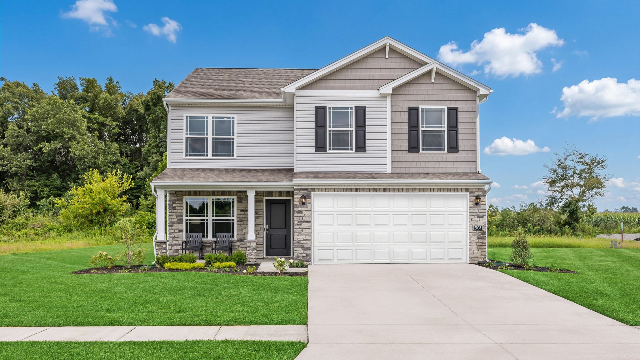 Bellamy model home for sale in Champions Run of Memphis, Indiana with gray siding, stone accents, covered front porch, and 2-car attached garage.