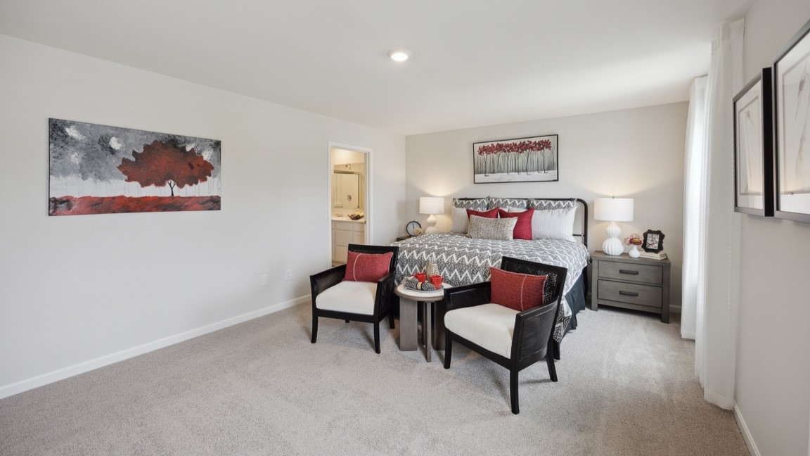 Primary bedroom with king size bed and 2 accent chairs at foot of bed