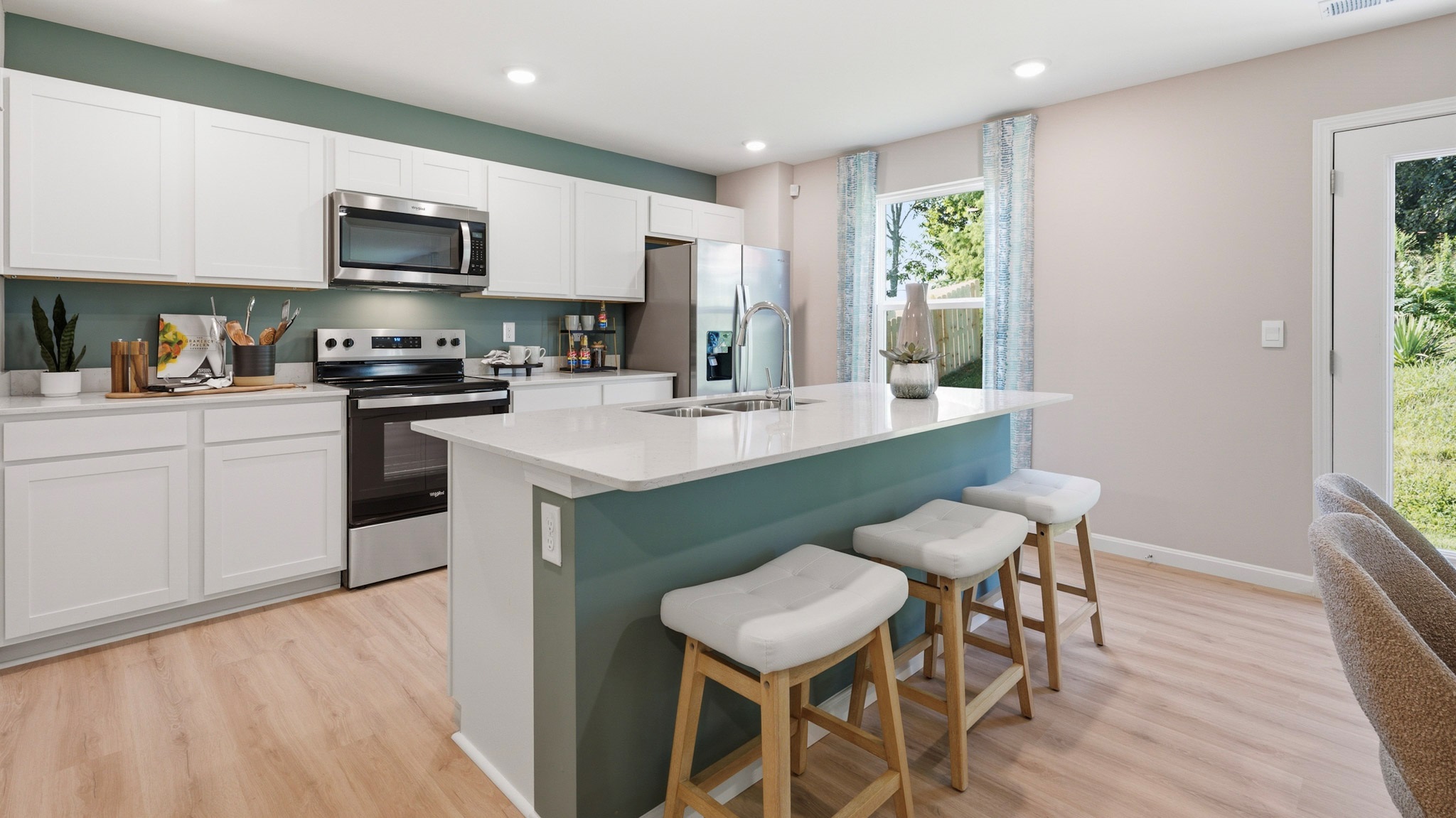 Spacious kitchen with white cabinets, quartz countertops, and stainless-steel appliances.