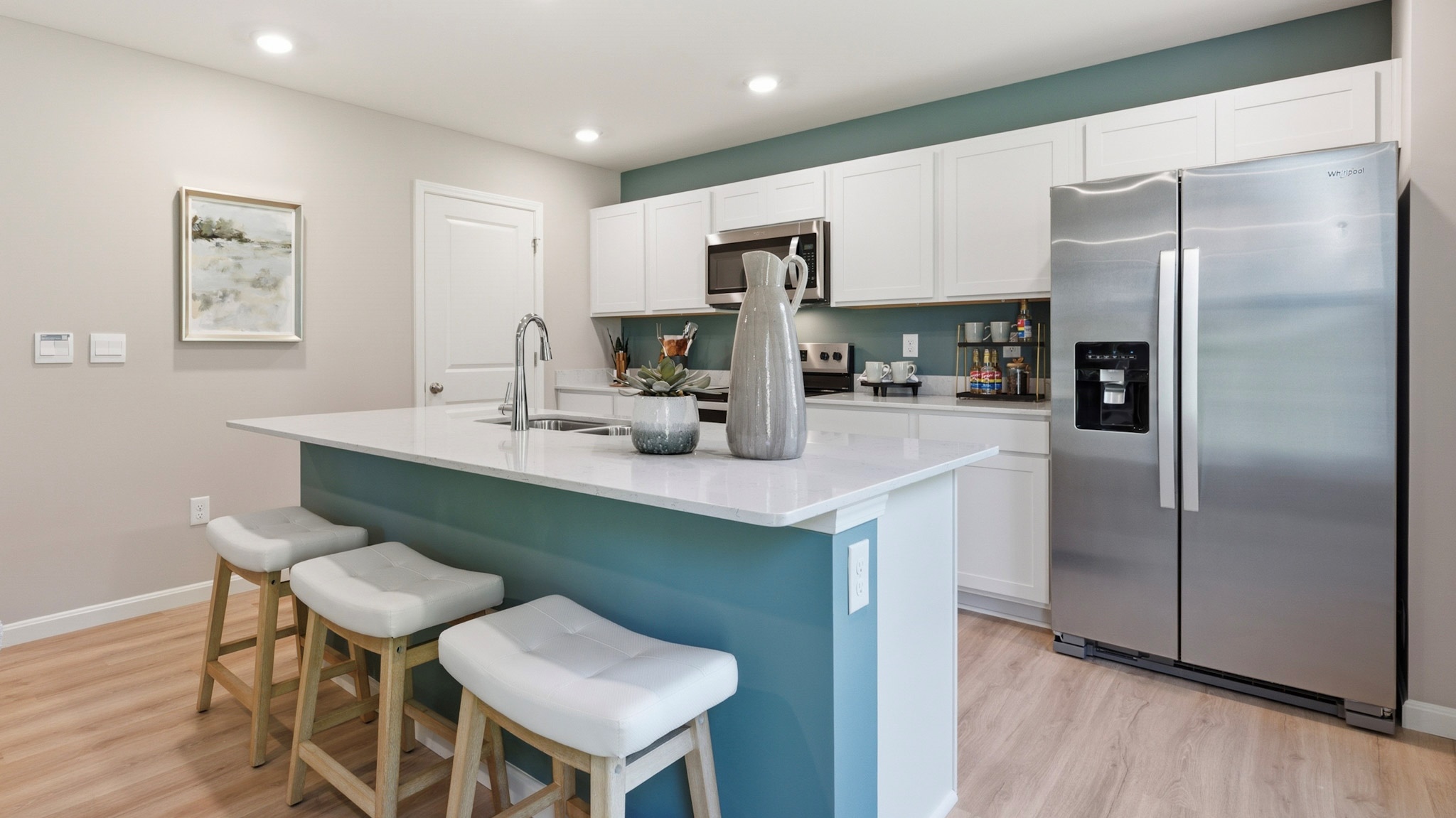 Spacious kitchen with white cabinets, quartz countertops, and stainless-steel appliances.