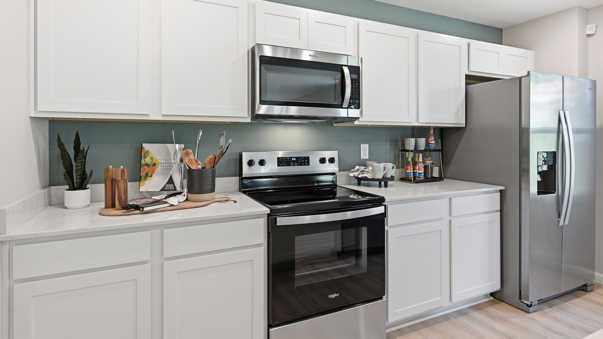 Spacious kitchen with white cabinets, quartz countertops, and stainless-steel appliances.